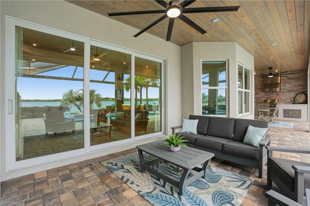 Covered patio featuring wood-finish ceiling, paver flooring, and built-in outdoor kitchen with stone accent wall