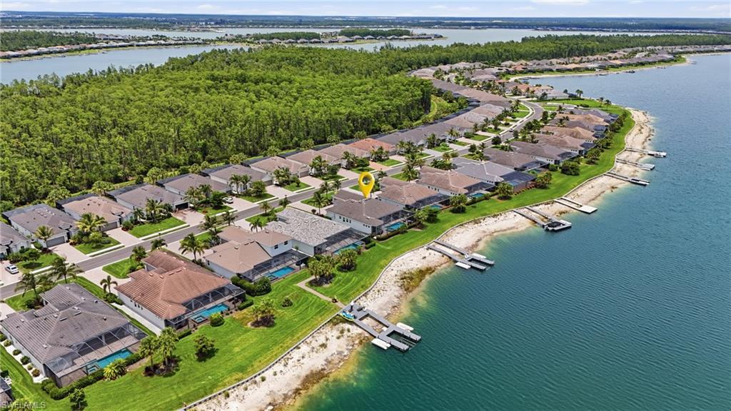 Waterfront property featuring a private dock, screened-in swimming pool, paved driveway, and mature landscaping