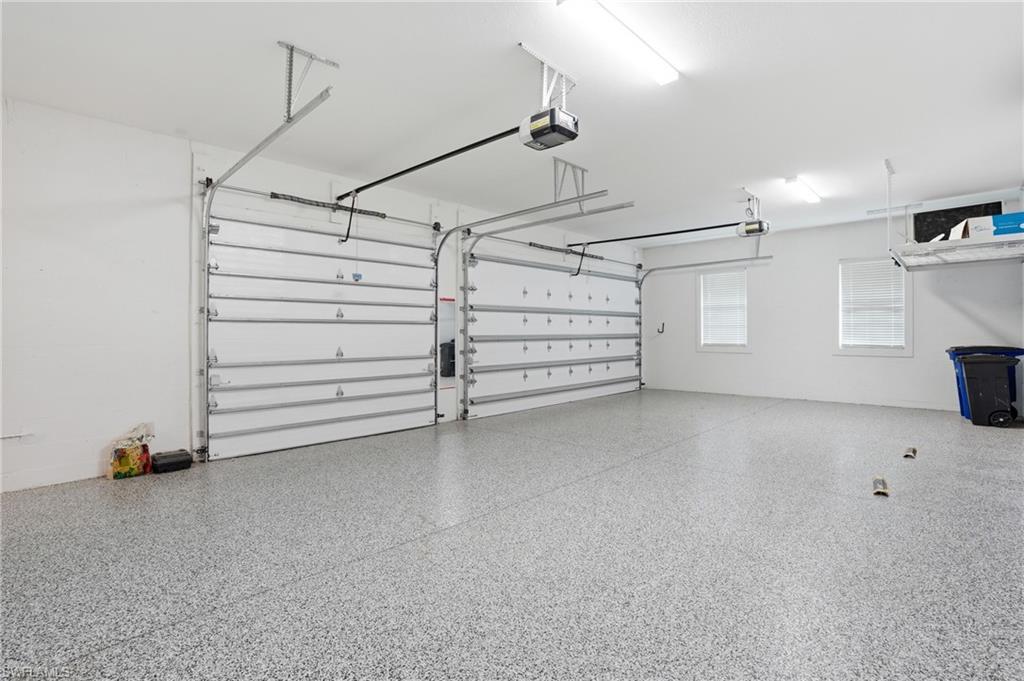 Spacious two-car garage featuring a speckled epoxy floor coating, two overhead garage door openers, and two windows