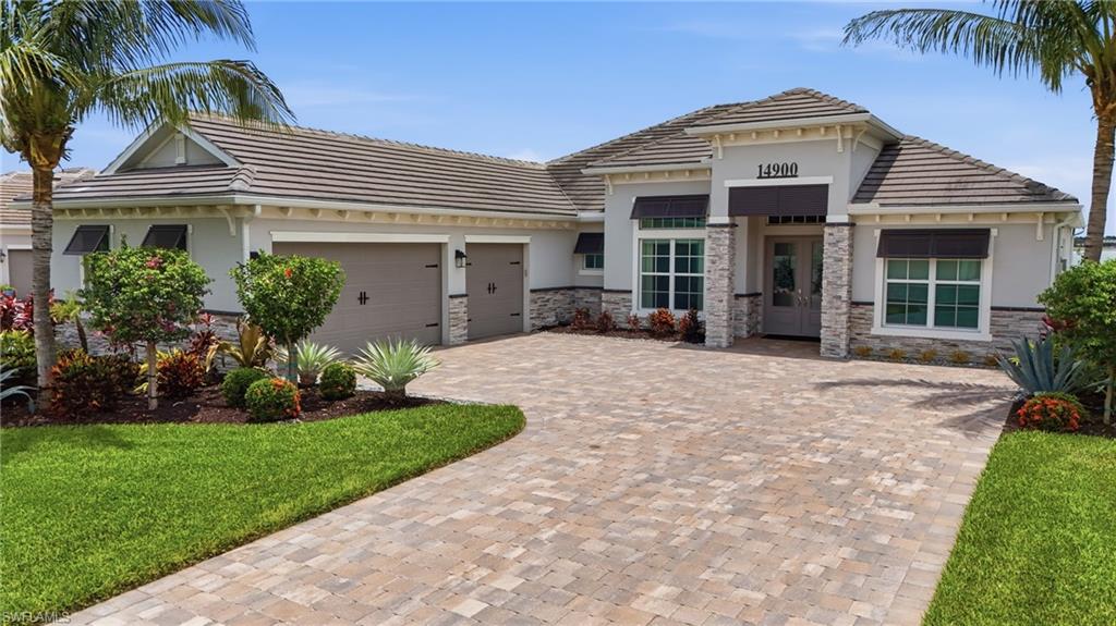 Stucco exterior with stone accents, a tiled roof, and a paver driveway