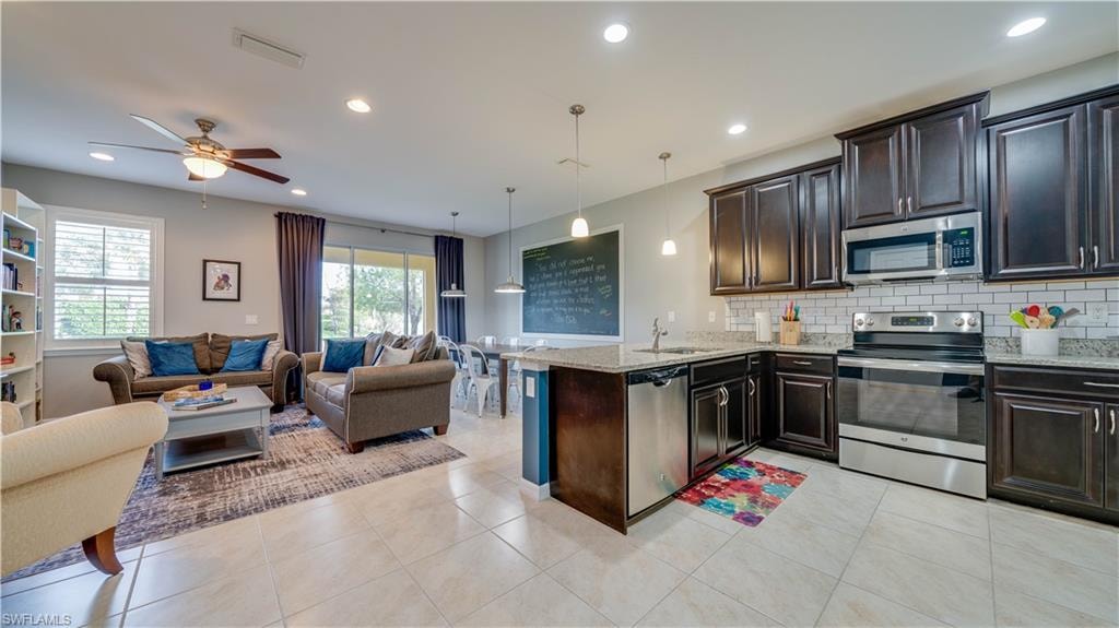 Kitchen with kitchen peninsula, a wealth of natural light, stainless steel appliances, and hanging light fixtures