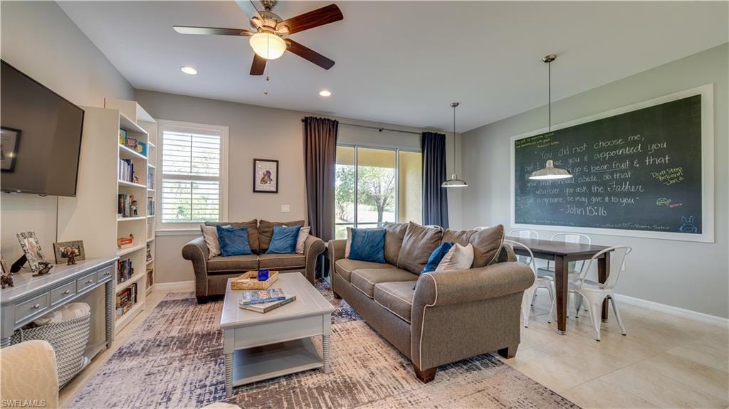Living room with light tile patterned flooring, a wealth of natural light, and ceiling fan