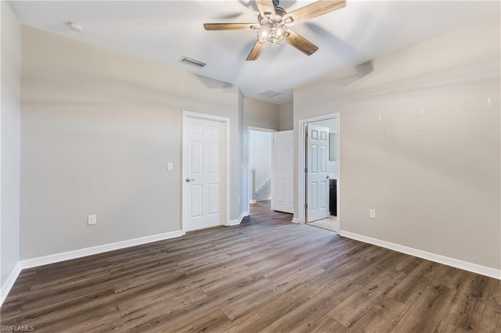 Unfurnished bedroom with wood finished floors, ceiling fan, and ensuite bathroom
