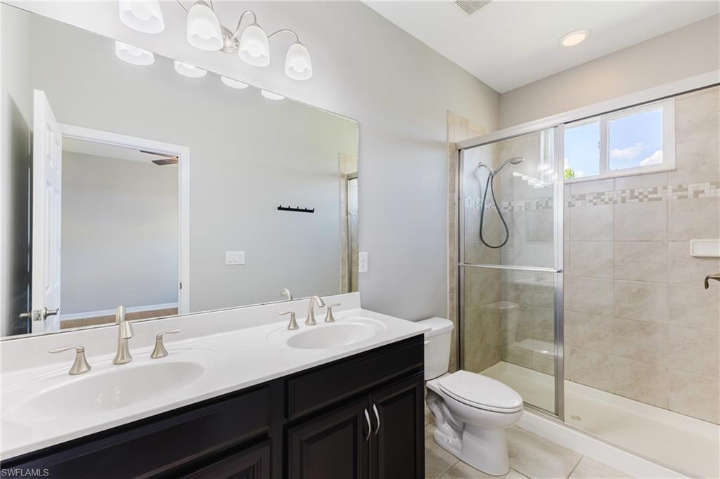 Bathroom with double vanity, a stall shower, light tile patterned floors, and recessed lighting