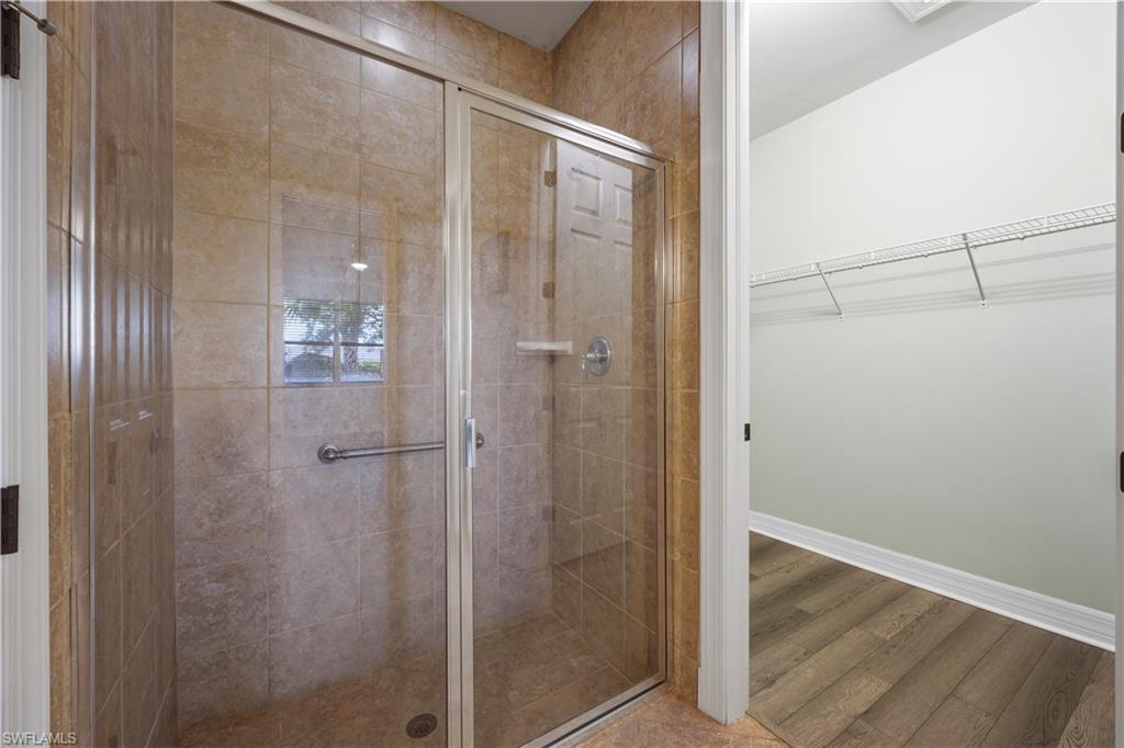 Glass-enclosed shower with full tile surround and grab bar