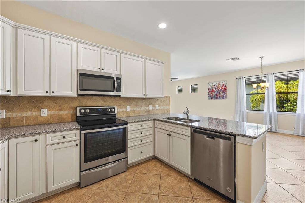 Kitchen featuring white cabinetry, stainless steel appliances, granite countertops, and a tiled backsplash