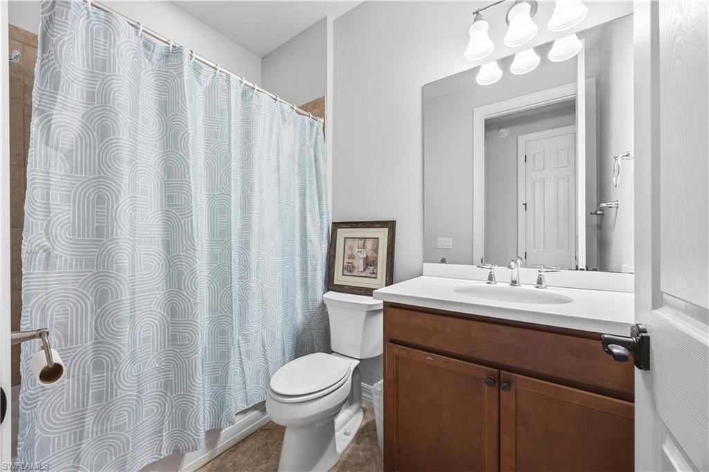 Bathroom featuring a wood-finish vanity with a white countertop and integrated sink, a large mirror, and overhead vanity lighting