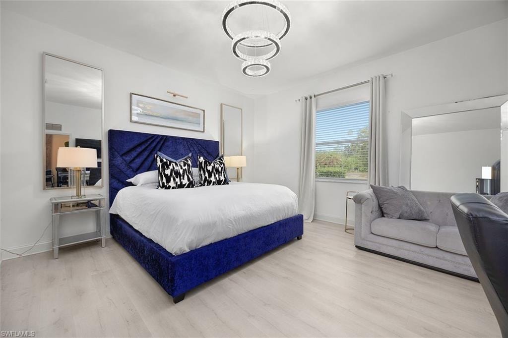 Spacious room featuring light wood-finish flooring, a window with blinds and drapes, and a contemporary chandelier light fixture