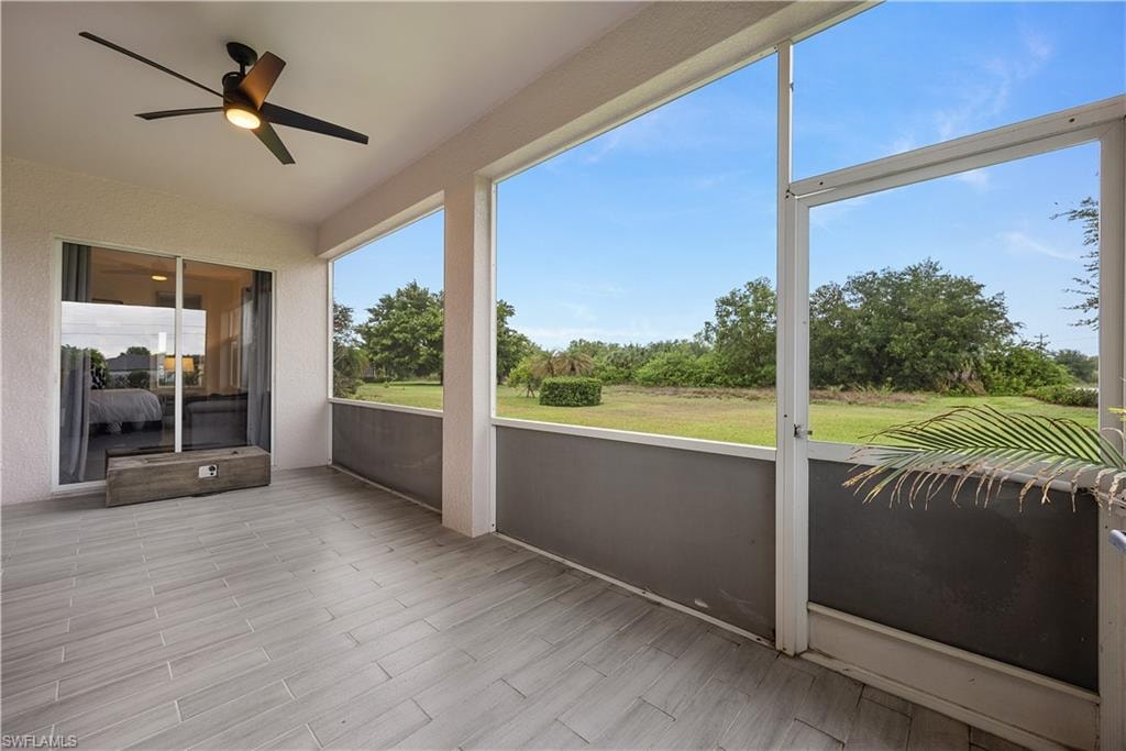 Screened lanai featuring wood-finish tile flooring and a ceiling fan with integrated lighting