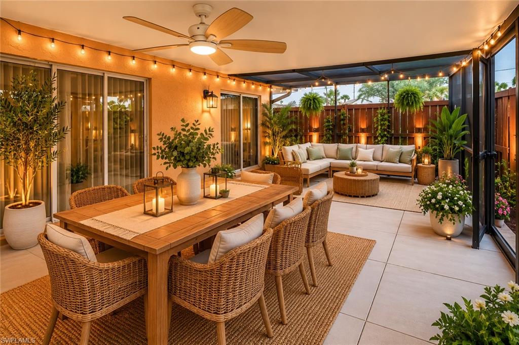 Spacious covered patio featuring a dining area with a wood table, a lounge area with an L-shaped sectional, a ceiling fan, string lighting, and extensive privacy fencing
