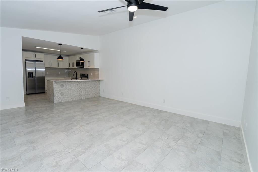 Open concept living area featuring light gray tile flooring and a ceiling fan with black blades