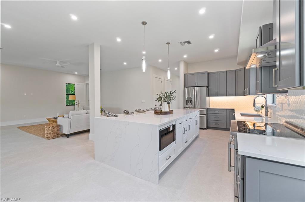 Kitchen featuring stainless steel appliances, light stone counters, pendant lighting, tasteful backsplash, and recessed lighting