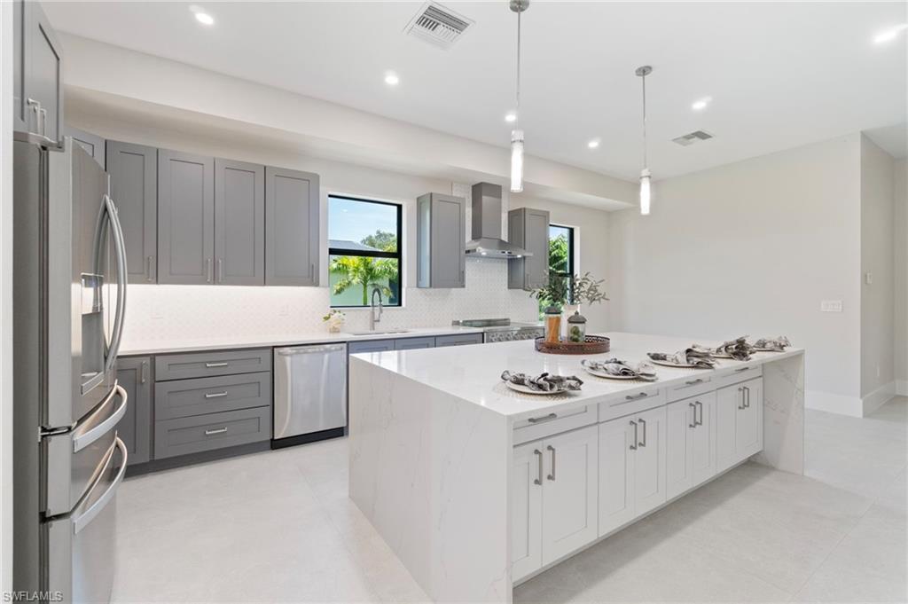 Kitchen featuring light stone countertops, gray cabinetry, decorative backsplash, appliances with stainless steel finishes, and recessed lighting