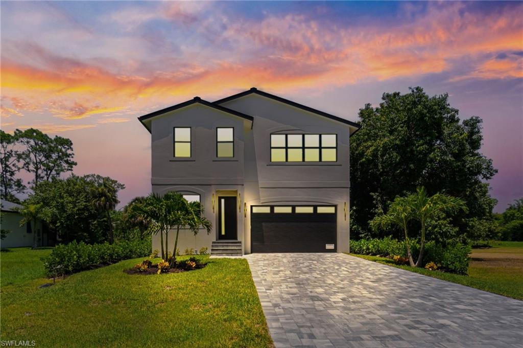 View of front of property with decorative driveway, a garage, stucco siding, and a front yard