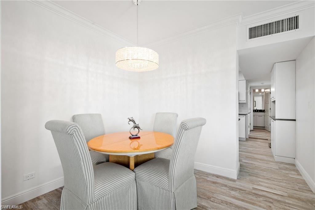 Dining space with ornamental molding and light hardwood / wood-style flooring