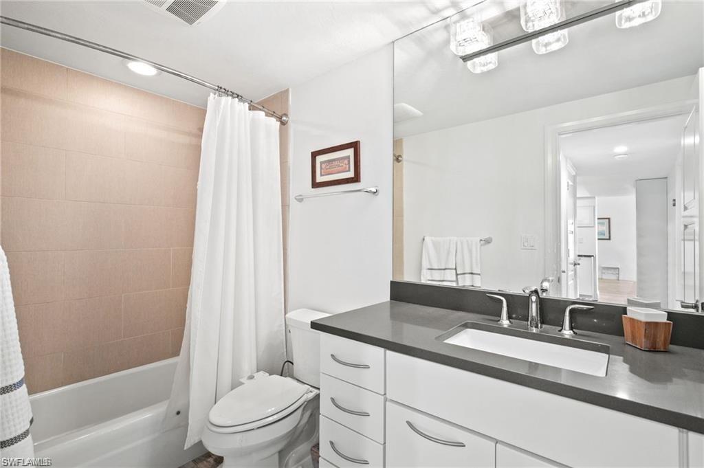 Full bathroom featuring shower / bathtub combination with curtain, toilet, and oversized vanity