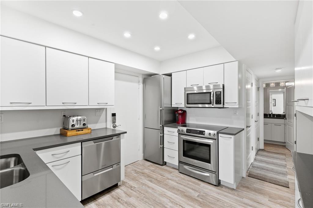 Kitchen with white cabinets, appliances with stainless steel finishes, and light hardwood / wood-style floors