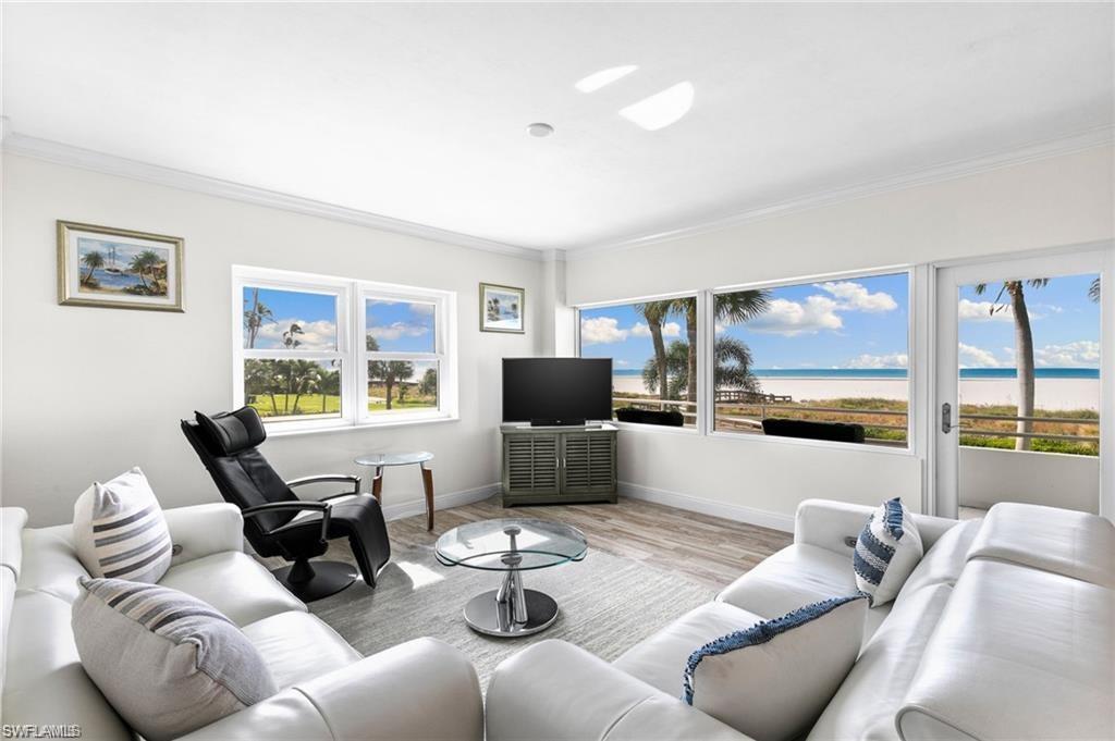 Living room featuring a healthy amount of sunlight, wood-type flooring, a water view, and crown molding