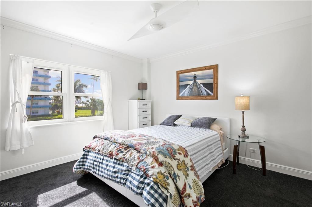 Bedroom featuring ornamental molding, dark colored carpet, and ceiling fan