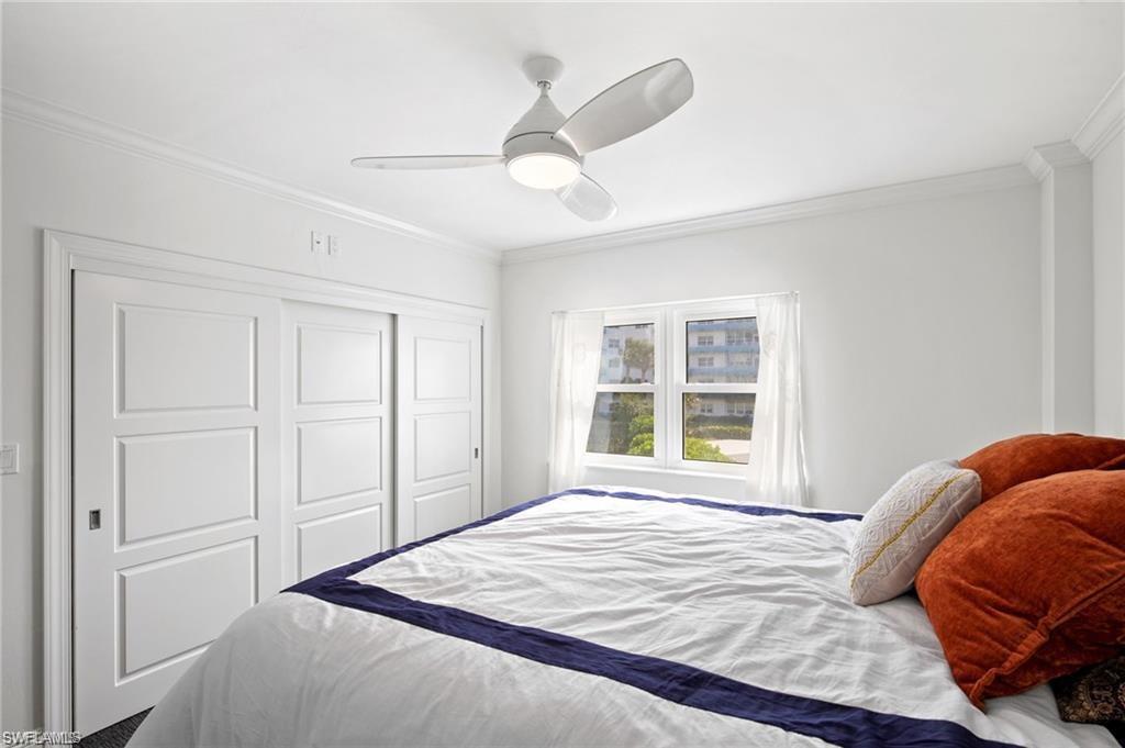 Bedroom with ornamental molding, ceiling fan, and a closet