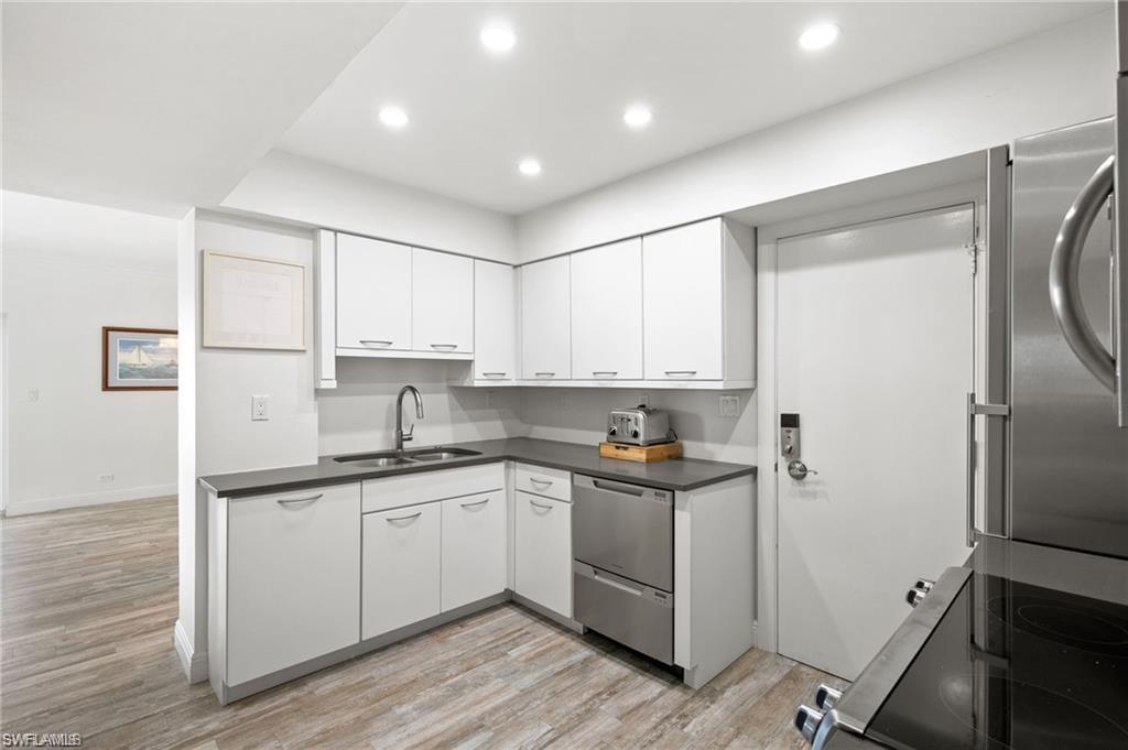 Kitchen featuring appliances with stainless steel finishes, light hardwood / wood-style floors, sink, and white cabinetry