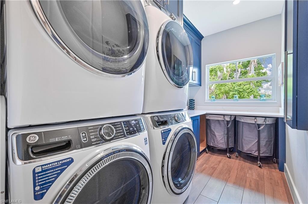 Dedicated laundry area featuring stacked front-load appliances and wood-finish flooring