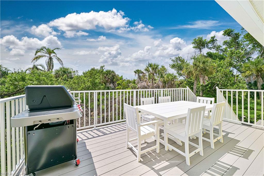 Spacious outdoor deck featuring composite decking, white railing, and extensive tropical landscaping