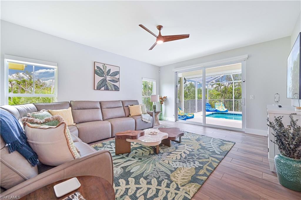 Spacious interior room featuring wood-finish flooring, a contemporary ceiling fan, and large windows