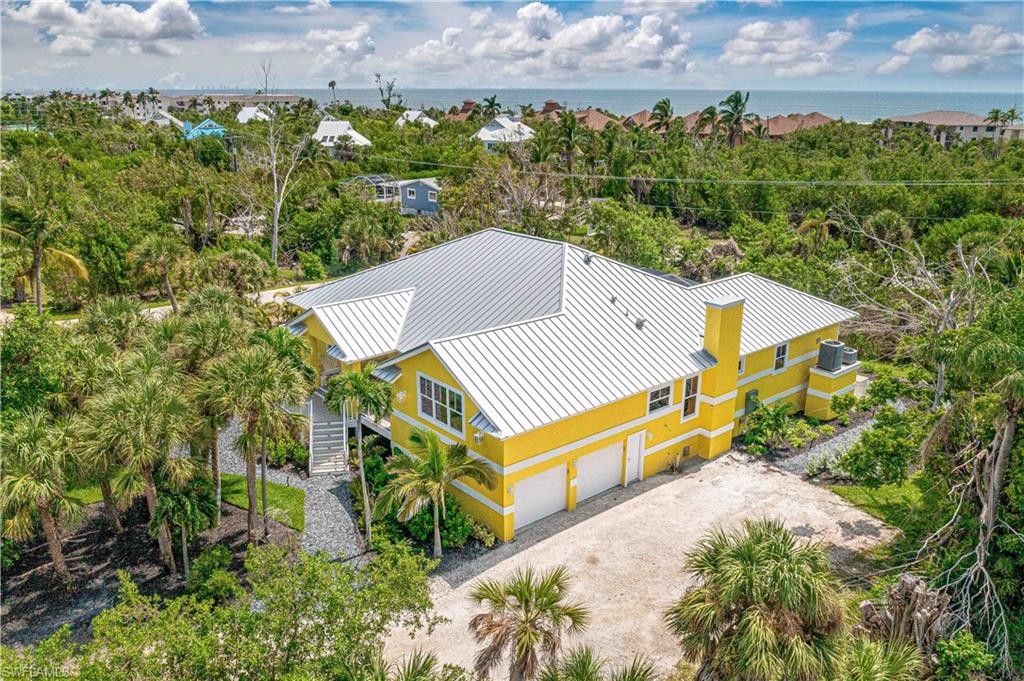 Two-story residence featuring a vibrant yellow exterior and a silver metal roof