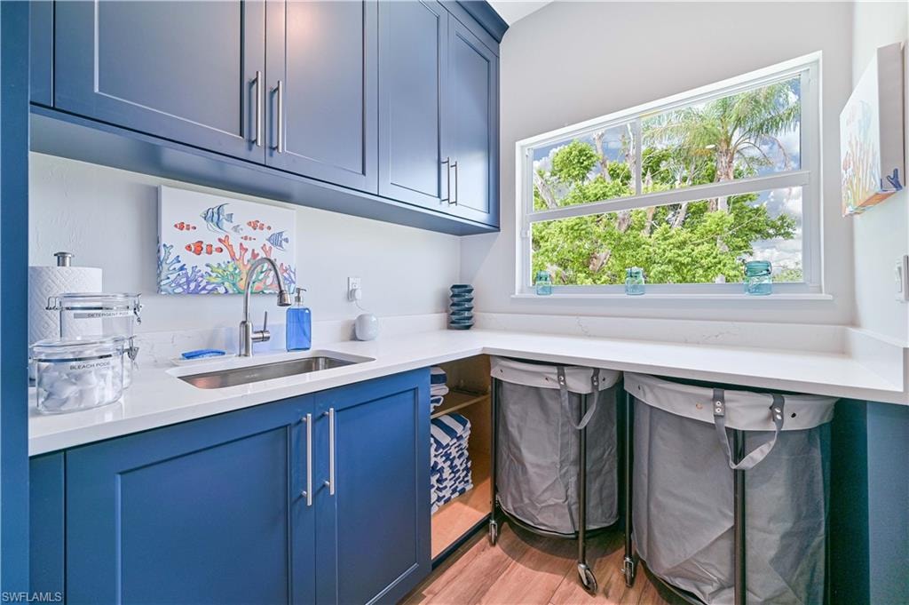 Laundry area featuring blue shaker-style cabinetry with brushed nickel hardware, white countertops, and a stainless steel sink with a gooseneck faucet