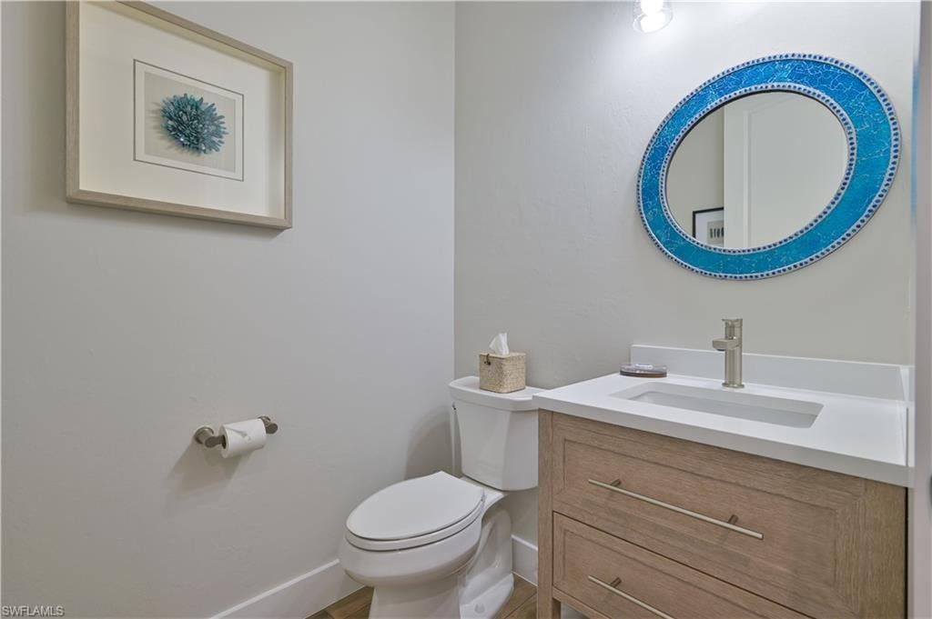 Bathroom featuring a wood-finish vanity with integrated sink, white countertop, and brushed nickel faucet