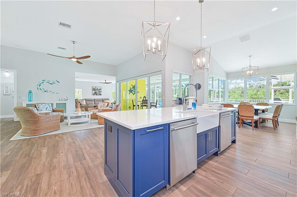 Open-concept kitchen featuring a large central island with white countertop, integrated farmhouse sink, and stainless steel appliances