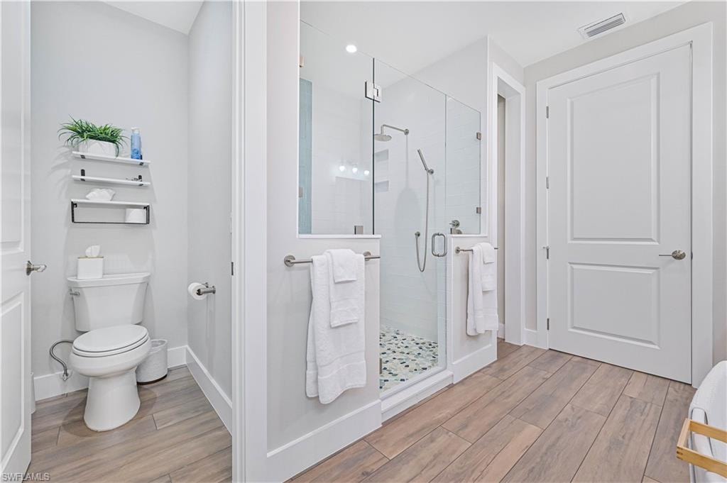 Modern bathroom featuring a frameless glass shower enclosure with a stone pebble floor, white subway tile surround, and dual shower heads