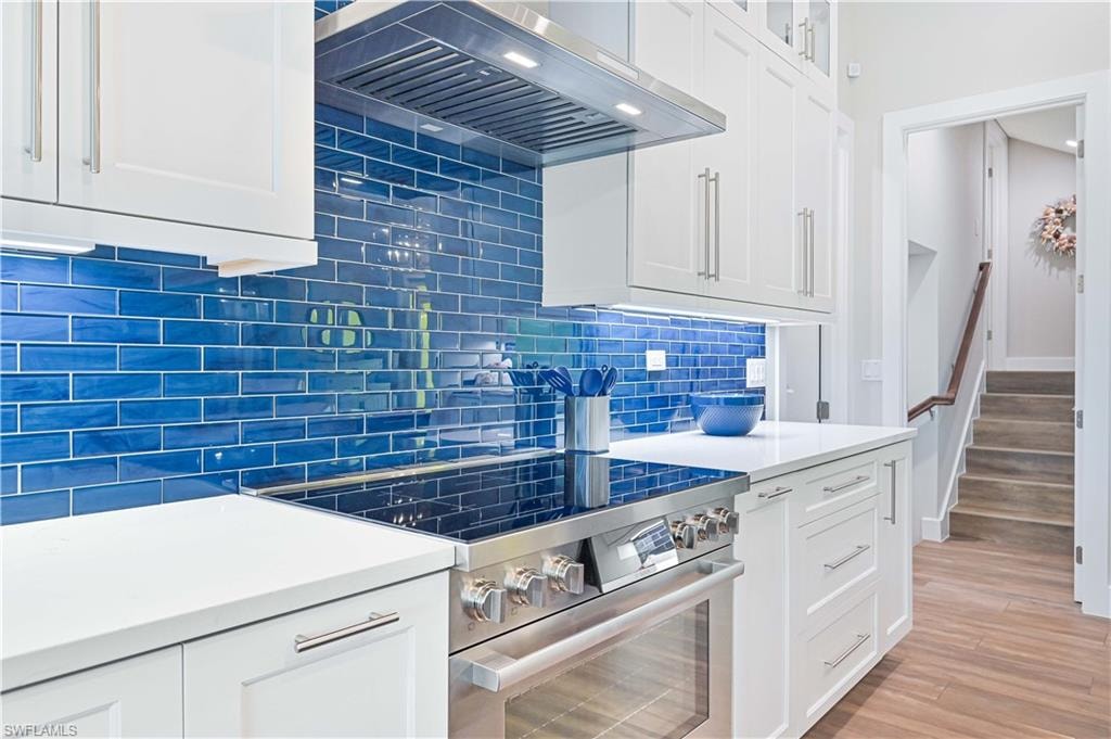 Kitchen featuring a blue subway tile backsplash, white cabinetry with brushed nickel hardware, and white countertops