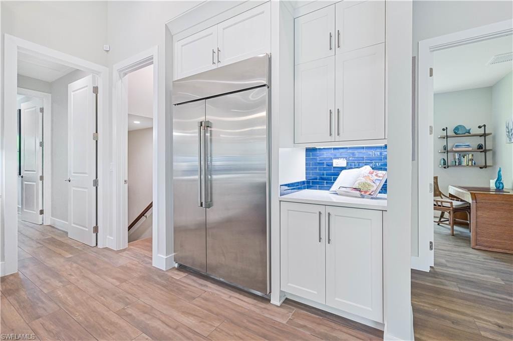 Integrated stainless steel refrigerator framed by white cabinetry