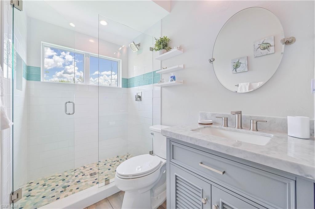 Contemporary bathroom featuring a glass-enclosed shower with mosaic tile flooring, a horizontal accent tile band, and a window for natural light