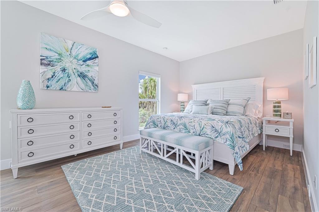 Light-filled bedroom featuring wood-finish flooring, a ceiling fan, and a window with natural light