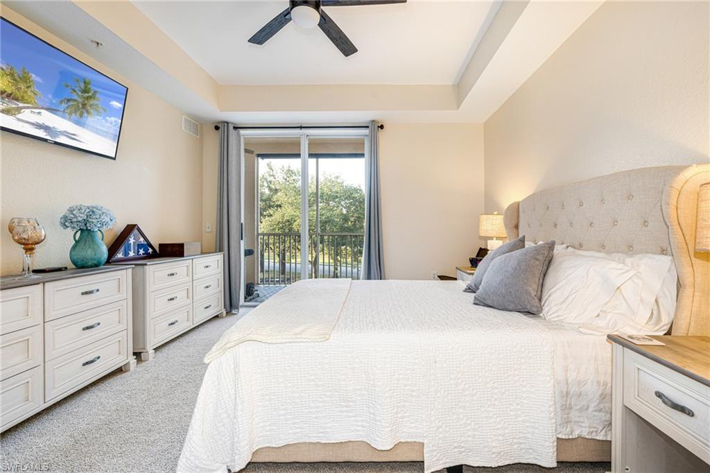 Recessed ceiling with a central fan, light-colored carpet flooring, and private balcony access through sliding glass doors