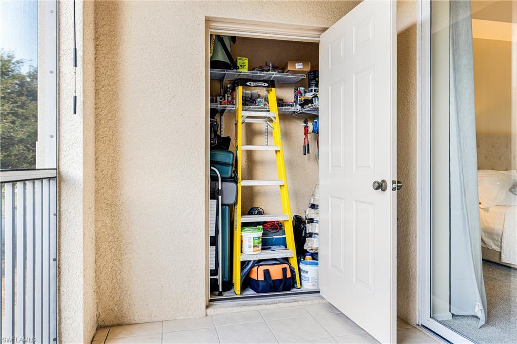 Outdoor storage closet featuring metal shelving, a solid white panel door, and exterior stucco finish