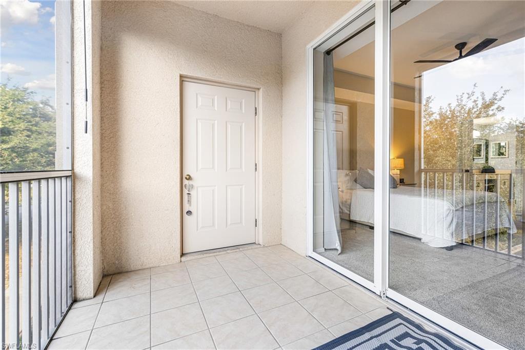 Tiled balcony with a white paneled door, sliding glass doors, and a metal railing