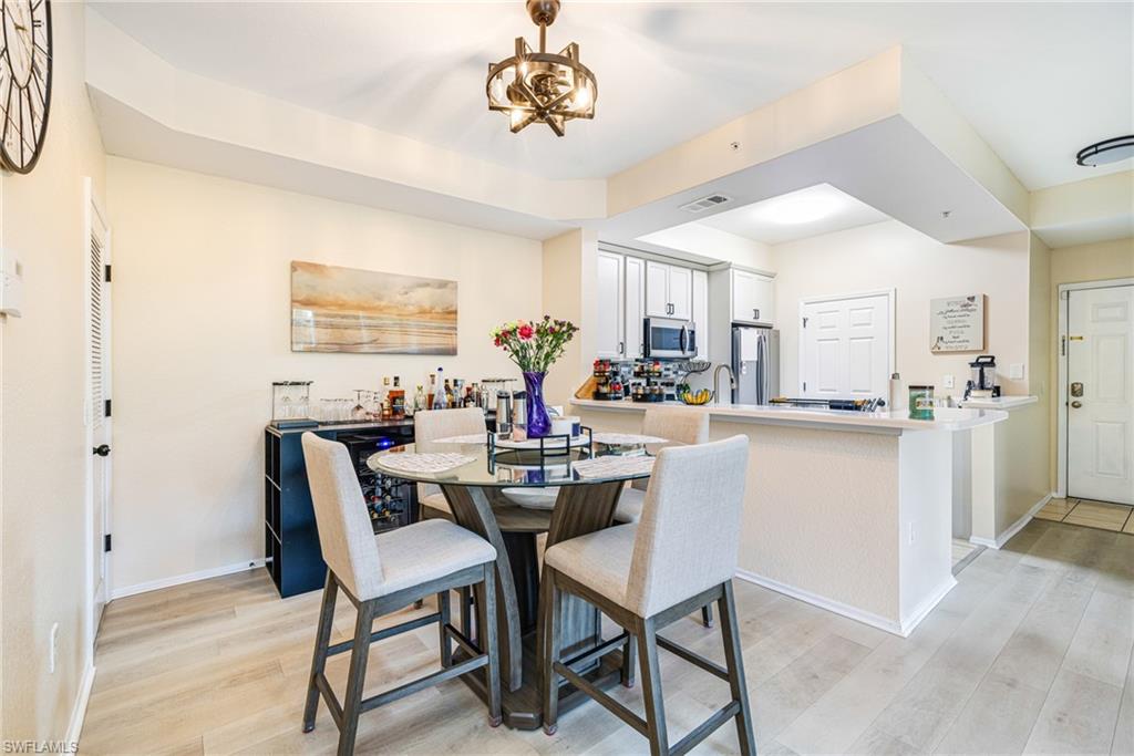 Dining area featuring wood-finish flooring, a built-in beverage cooler, and a decorative ceiling light fixture