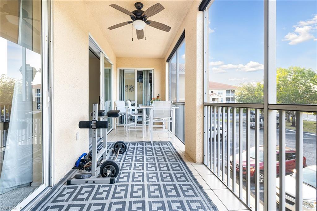 Screened balcony featuring a ceiling fan, white tile flooring, and sliding glass doors