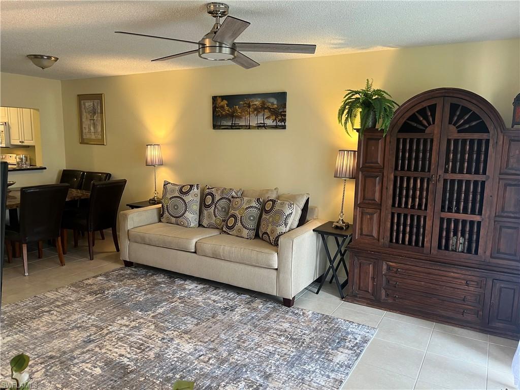 Living area featuring light tile patterned floors, ceiling fan, and a textured ceiling