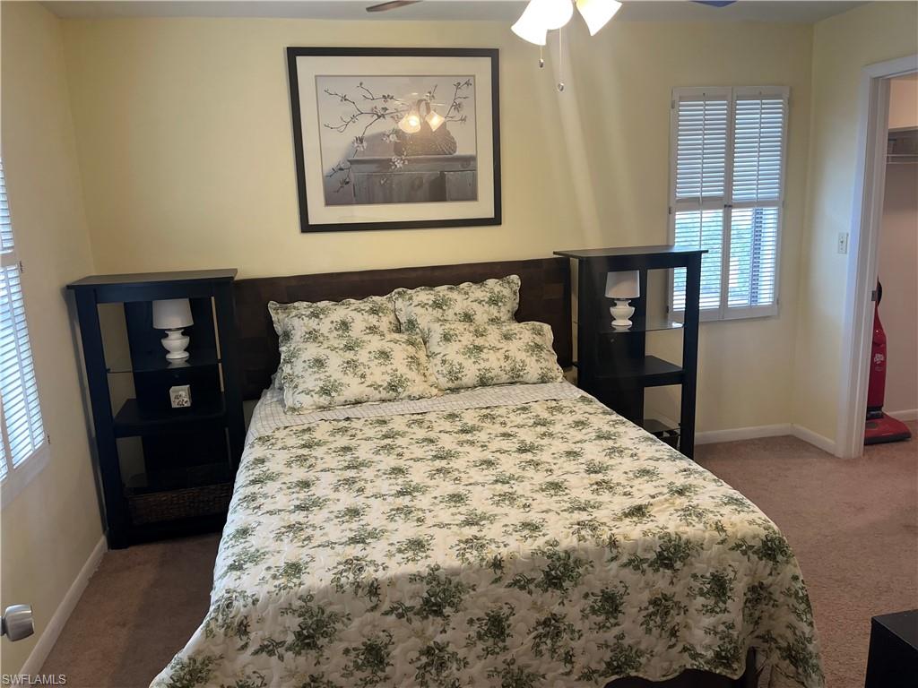 Bedroom featuring carpet, multiple windows, and baseboards