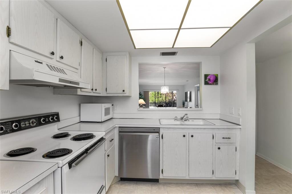 Kitchen with range, white cabinets, sink, light tile patterned flooring, and dishwasher