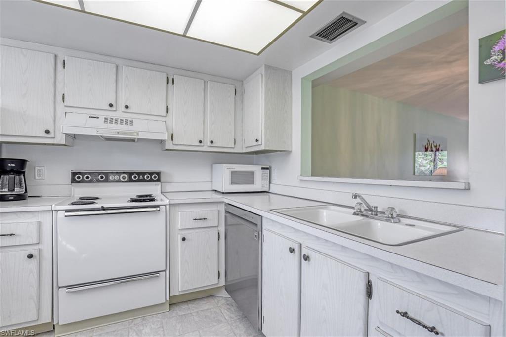 Kitchen with sink, white appliances, custom exhaust hood, and light tile patterned floors
