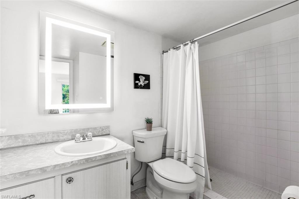 Bathroom featuring curtained shower, toilet, and vanity