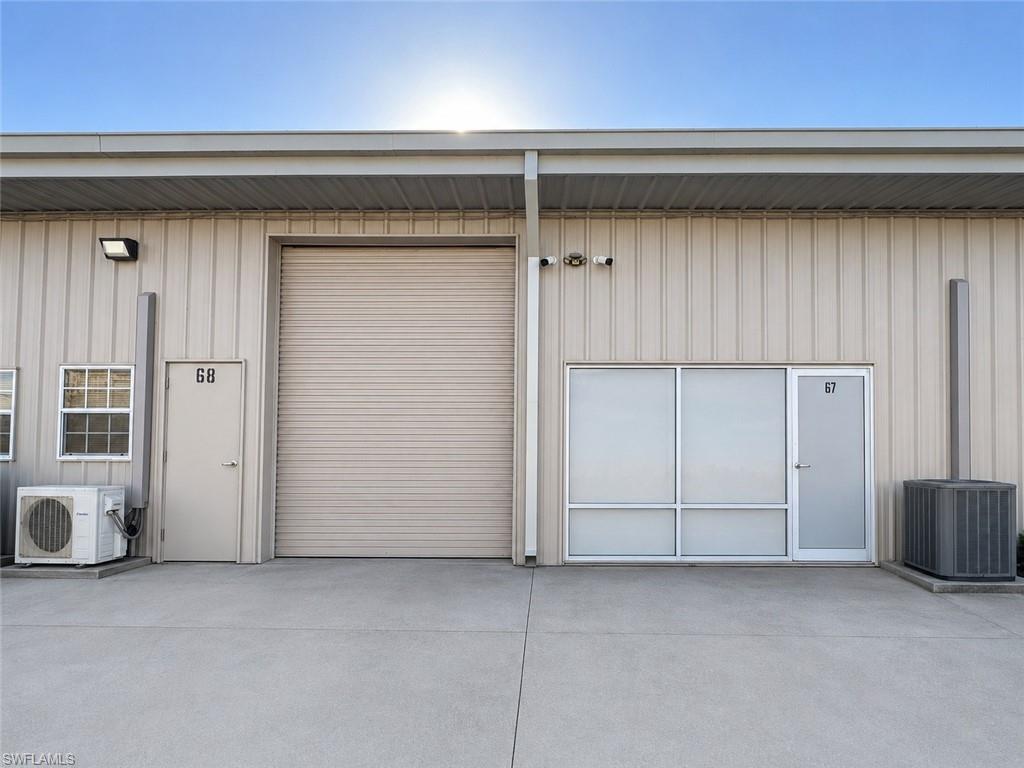 Exterior facade featuring a roll-up bay door, two pedestrian entry doors, and aluminum-framed windows