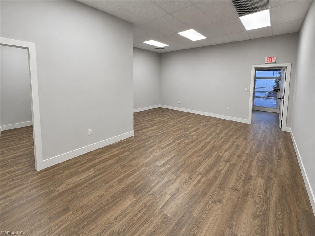 Open-concept interior featuring wood-finish flooring, light gray walls, white baseboards, and a dropped ceiling with recessed lighting
