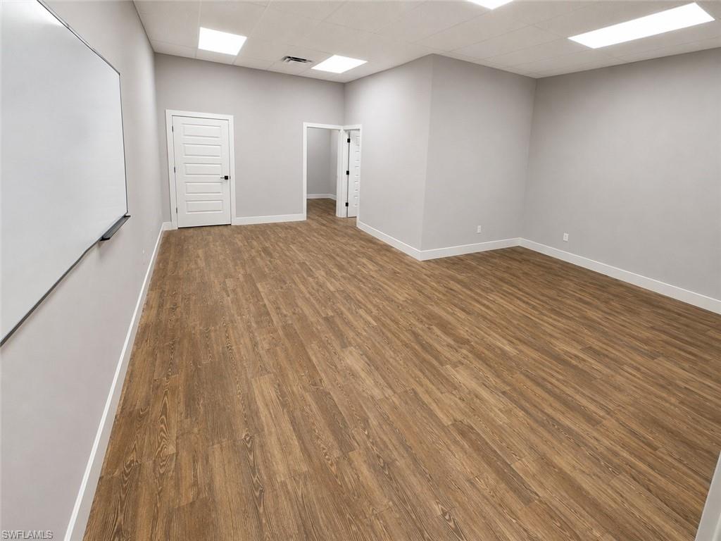 Spacious room featuring wood-finish flooring and light gray walls